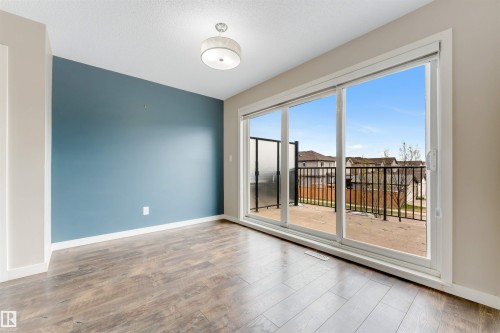 Wood-finish flooring, accent wall, ceiling-mounted light fixture, sliding glass door, and a private balcony - 3340 15A Avenue Nw, Edmonton, AB 