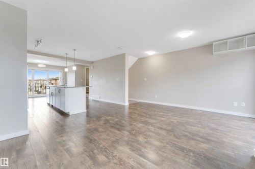 Open-concept living area featuring wood-finish flooring, recessed lighting, and a kitchen island with pendant lights - 3340 15A Avenue Nw, Edmonton, AB 