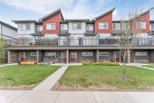 Contemporary townhome exterior featuring multi-toned siding, stone accents, and red entry doors - 3340 15A Avenue Nw, Edmonton, AB 