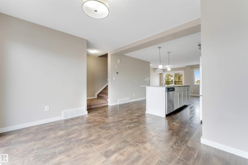 Wood-finish flooring, recessed ceiling lighting, kitchen island with integrated dishwasher, sliding glass doors, and light-toned wall paint - 3340 15A Avenue Nw, Edmonton, AB 