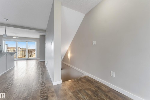 Wood-finish flooring throughout, sliding glass door leading to a balcony, modern pendant lighting, and neutral wall tones - 3340 15A Avenue Nw, Edmonton, AB 
