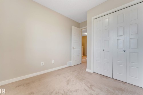 Neutral wall paint, plush carpeting, white bi-fold closet doors, and a paneled interior door - 3340 15A Avenue Nw, Edmonton, AB 