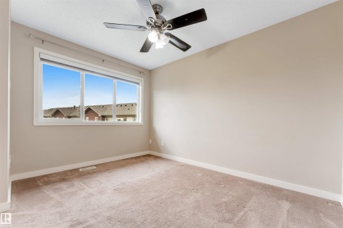 Carpeted flooring, neutral wall color, ceiling fan with integrated lighting, and a large multi-pane window - 3340 15A Avenue Nw, Edmonton, AB 
