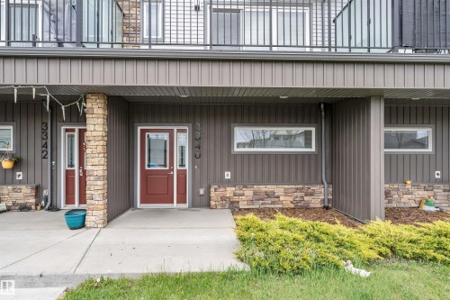Red-toned entry door with sidelights, stone veneer accents, and horizontal siding - 3340 15A Avenue Nw, Edmonton, AB 