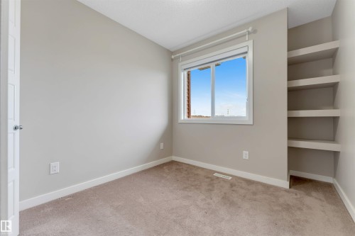 Recessed built-in shelving, neutral-toned carpeting, and a white-framed window - 3340 15A Avenue Nw, Edmonton, AB 