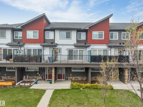 Contemporary townhome exterior featuring red siding accents, light grey siding, and dark trim - 3340 15A Avenue Nw, Edmonton, AB 