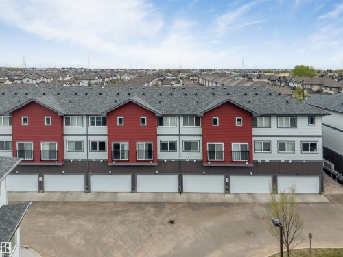 Row of townhomes featuring multi-tone siding, individual garage doors, and upper-level balconies with dark railings - 3340 15A Avenue Nw, Edmonton, AB 