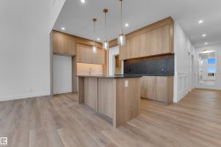 Open-concept kitchen with wood-finish cabinetry, a central island, recessed lighting, and pendant fixtures - 