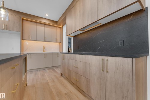 Wood-finish flooring, custom cabinetry with gold-tone hardware, dark stone countertops, dark stone backsplash, and recessed lighting - 236 Linden Loop, Leduc, AB 