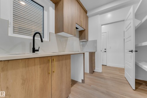 Wood-finish cabinetry with brass hardware, undermount sink, and a matte black faucet - 236 Linden Loop, Leduc, AB 