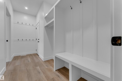 Built-in mudroom bench with storage, integrated coat hooks, recessed lighting, and wood-finish flooring - 236 Linden Loop, Leduc, AB 