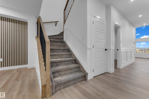 Staircase featuring carpeted treads and wood handrails with black metal balusters - 236 Linden Loop, Leduc, AB 