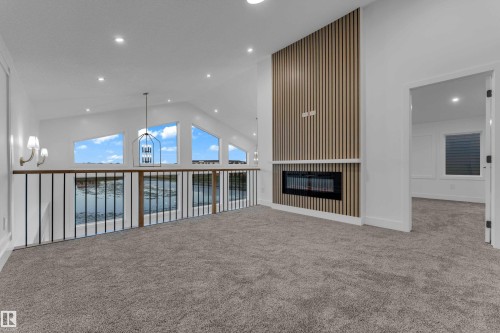 Vaulted ceiling with recessed lighting, linear electric fireplace, wood slat accent wall, and trapezoidal windows - 236 Linden Loop, Leduc, AB 