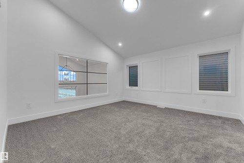 Vaulted ceiling, two recessed lights, flush-mount ceiling light, paneled wall detailing, and grey carpeting - 236 Linden Loop, Leduc, AB 
