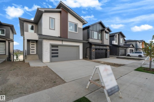 Contemporary exterior with mixed material facade, integrated garage, concrete driveway, and front entry with modern door - 236 Linden Loop, Leduc, AB 