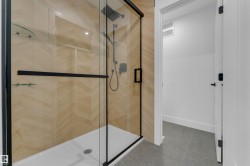 Enclosed shower with clear glass and matte black framing, chevron-patterned tile surround, and a white shower pan - 