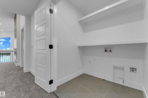 Laundry area featuring two built-in shelves, tile flooring, and clean white walls - 236 Linden Loop, Leduc, AB 