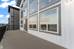 Modern exterior featuring expansive multi-pane windows with aluminum framing, horizontal corrugated metal siding accents, and a spacious concrete deck with metal railings overlooking the surrounding landscape - 