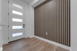 Modern white entry door with frosted glass inserts, wood-finish flooring, and a textured accent wall - 