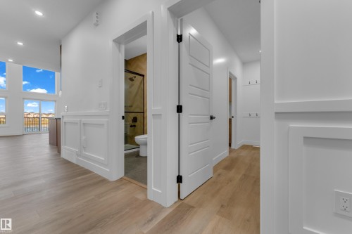 Light wood-finish flooring throughout, white paneled walls, and white interior doors with black hardware - 236 Linden Loop, Leduc, AB 