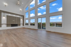 Vaulted ceiling with a contemporary chandelier, wood-finish flooring, built-in fireplace, and expansive windows - 