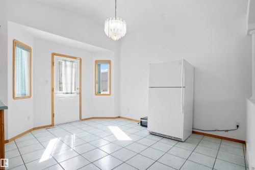 White tile flooring, a built-in refrigerator, and a decorative pendant light fixture - 2915 151A Avenue Nw, Edmonton, AB 