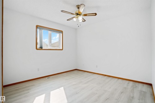 Light wood-finish flooring, a window with wood trim, and a ceiling fan with integrated lighting - 2915 151A Avenue Nw, Edmonton, AB 