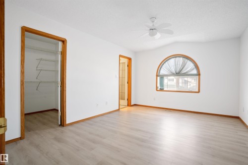 Light wood-finish flooring, a ceiling fan, a vaulted ceiling, a half-round window, and a walk-in closet with wire shelving - 2915 151A Avenue Nw, Edmonton, AB 