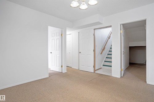 Spacious upper-level bedroom featuring neutral wall finishes, neutral-toned carpet flooring, and multiple white six-panel doors providing access to adjacent spaces and storage areas - 2915 151A Avenue Nw, Edmonton, AB 