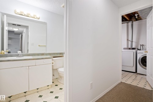 Bathroom vanity with a surface-mounted sink and wall-mounted light fixture - 2915 151A Avenue Nw, Edmonton, AB 