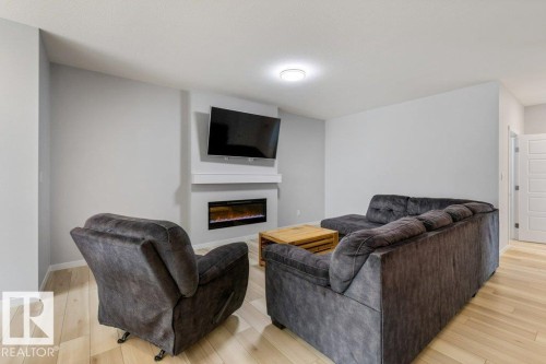 Living area featuring light wood-finish flooring and neutral wall tones - 7113 177A Avenue Nw, Edmonton, AB - Indoor Photo Showing Living Room With Fireplace
