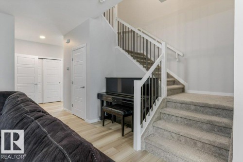 Interior staircase featuring carpeted treads and risers, white wood newel posts, and dark metal balusters - 7113 177A Avenue Nw, Edmonton, AB - Indoor Photo Showing Other Room