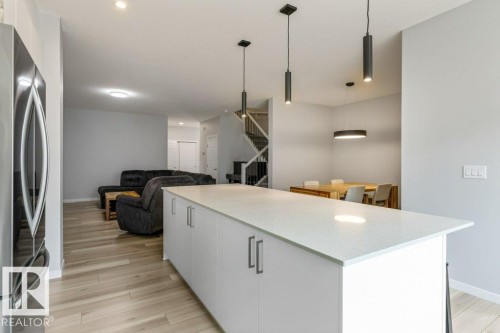 Central kitchen island with a light-toned countertop and white cabinetry - 7113 177A Avenue Nw, Edmonton, AB - Indoor Photo Showing Kitchen