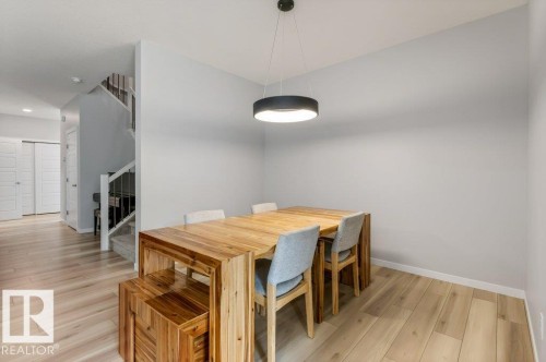 Dining area featuring light wood-finish flooring, a contemporary black pendant light fixture, and light gray wall paint - 7113 177A Avenue Nw, Edmonton, AB - Indoor Photo Showing Dining Room