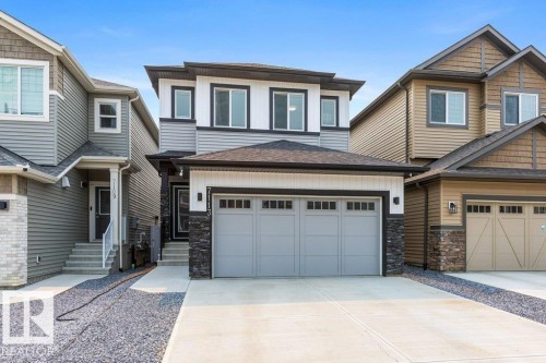 Modern two-story residence featuring a light gray garage door with window inserts, dark stone veneer accents, and white trim - 7113 177A Avenue Nw, Edmonton, AB - Outdoor With Facade