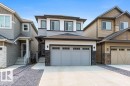 Modern two-story residence featuring a light gray garage door with window inserts, dark stone veneer accents, and white trim - 7113 177A Avenue Nw, Edmonton, AB  - Outdoor With Facade 