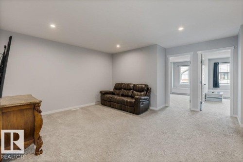 Spacious room with light gray walls, recessed lighting, and soft gray carpeting - 7113 177A Avenue Nw, Edmonton, AB - Indoor
