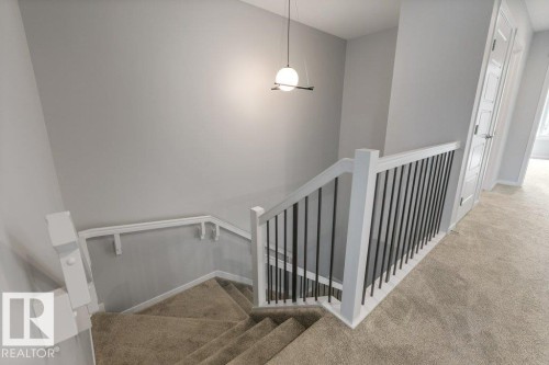 Carpeted staircase featuring a modern black and white spindle railing - 7113 177A Avenue Nw, Edmonton, AB - Indoor Photo Showing Other Room