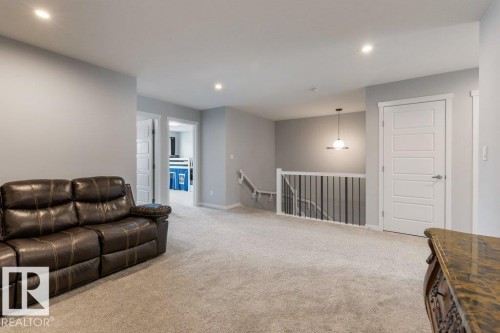 Spacious carpeted common area featuring recessed lighting, a modern pendant light, and crisp white trim - 7113 177A Avenue Nw, Edmonton, AB - Indoor