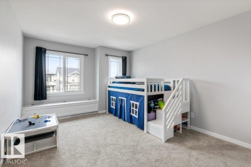 Spacious room featuring light gray wall paint, light-colored carpet flooring, a large window with a built-in window seat, and a flush-mount ceiling light fixture - 7113 177A Avenue Nw, Edmonton, AB - Indoor