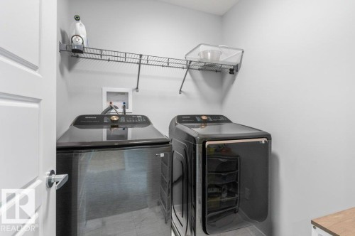 Dedicated laundry space featuring a white paneled door, light gray wall paint, and overhead wire shelving - 7113 177A Avenue Nw, Edmonton, AB - Indoor Photo Showing Laundry Room