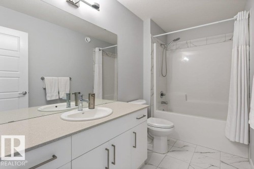 Full bathroom featuring a white vanity with a light-toned countertop, an oval undermount sink, and a chrome faucet - 7113 177A Avenue Nw, Edmonton, AB - Indoor Photo Showing Bathroom