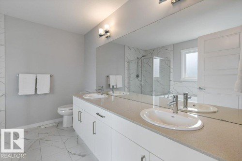 Double vanity with under-mount sinks, light-toned countertop, and white cabinetry - 7113 177A Avenue Nw, Edmonton, AB - Indoor Photo Showing Bathroom