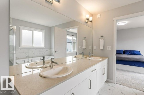 Double vanity with integrated sinks, light-toned countertop, and chrome faucets - 7113 177A Avenue Nw, Edmonton, AB - Indoor Photo Showing Bathroom