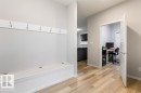 Entryway featuring wood-finish flooring, a built-in storage bench with flip-top access, and wall-mounted coat hooks - 7113 177A Avenue Nw, Edmonton, AB  - Indoor Photo Showing Other Room 