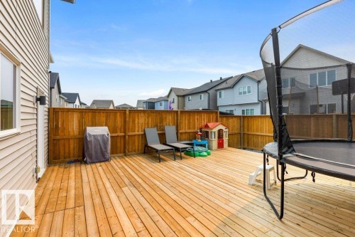Spacious wood deck with a perimeter wood fence, light-toned siding, and exterior lighting fixture - 7113 177A Avenue Nw, Edmonton, AB - Outdoor With Deck Patio Veranda With Exterior