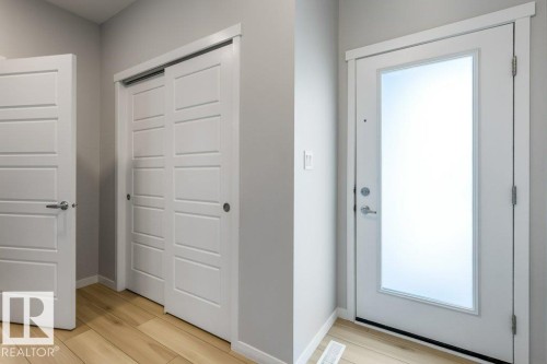 Entryway featuring a solid panel door, sliding closet doors, and wood-finish flooring - 7113 177A Avenue Nw, Edmonton, AB - Indoor Photo Showing Other Room