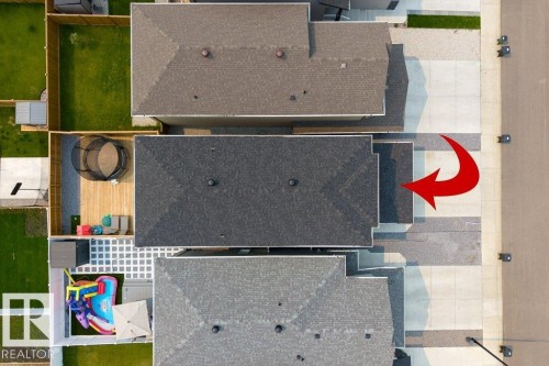 Aerial perspective showcasing the property's dark shingled roof, a paved driveway, and a fenced backyard with a wood deck - 7113 177A Avenue Nw, Edmonton, AB - 