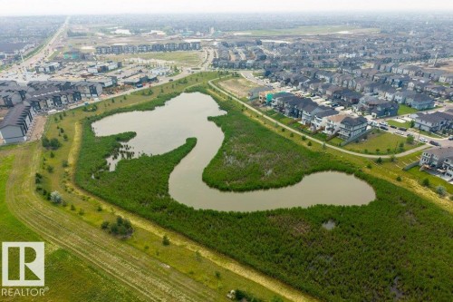 Aerial perspective of a developed residential area featuring a winding body of water and surrounding green spaces - 7113 177A Avenue Nw, Edmonton, AB - Outdoor With View