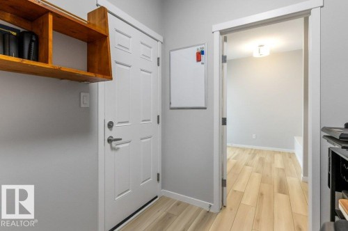 Interior entryway featuring a paneled door with brushed nickel hardware, light wood-finish flooring, light grey wall paint, and a built-in wood shelf - 7113 177A Avenue Nw, Edmonton, AB - Indoor Photo Showing Other Room